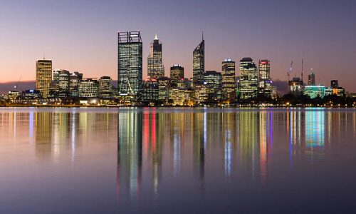 Perth city central business district skyline at twilight in Western Australia. The lights from the skyscrapers are reflecting in the Swan river at dusk which has a slight motion blur due to a long exposure. These are the tallest office buildings in Perth CBD.